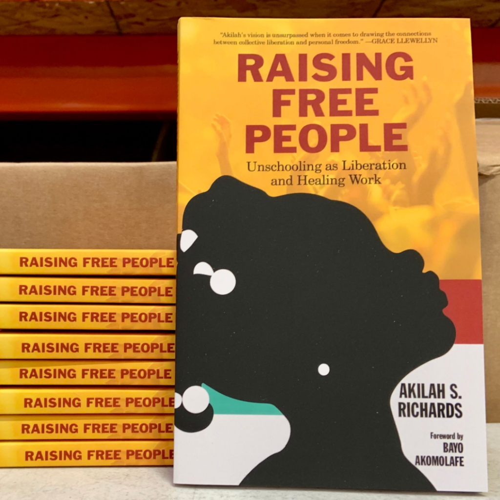 A pile of books shown by their spines, with one of the books leaning on the front with text Raising Free People by Akilah S. Richards